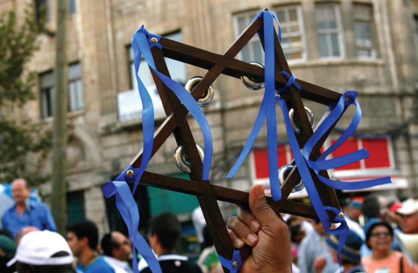 A christian reveler holds a Star of David while marching in an annual parade during Sukkot in Jerusalem in 2007 (photo credit: REUTERS)