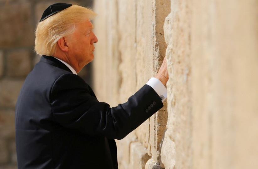 US President Donald Trump places a note in the stones of the Western Wall, Judaism's holiest prayer site, in Jerusalem's Old City May 22, 2017. (photo credit: REUTERS / JONATHAN ERNST)
