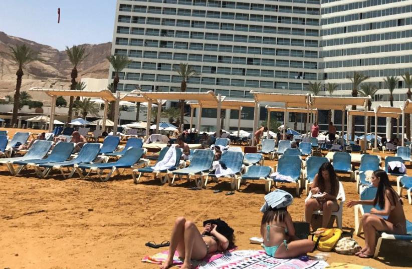 Guests enjoy a day at the beach (with the Crowne Plaza in the background) (photo credit: SETH J. FRANTZMAN)