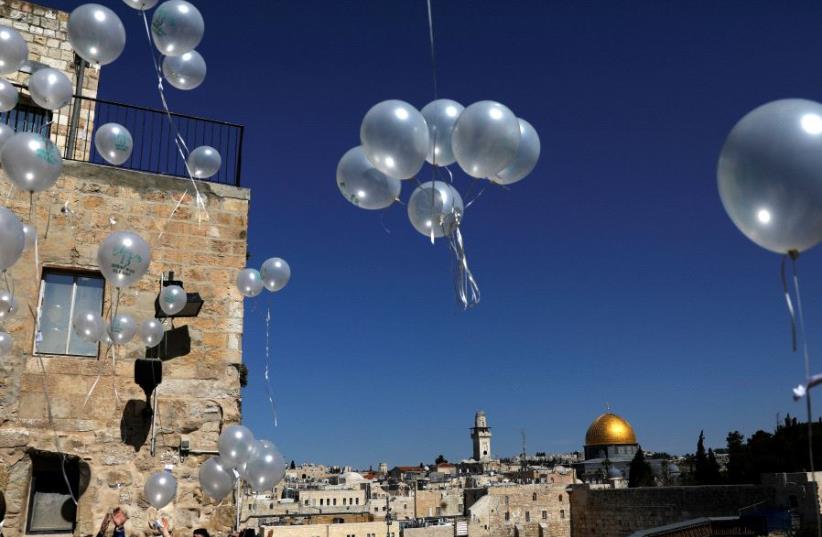 People release balloons as they celebrate a Bar Mitzva as the Western Wall and the Dome of the Rock are seen in the background, in Jerusalem's Old City (photo credit: REUTERS/Ronen Zvulun)