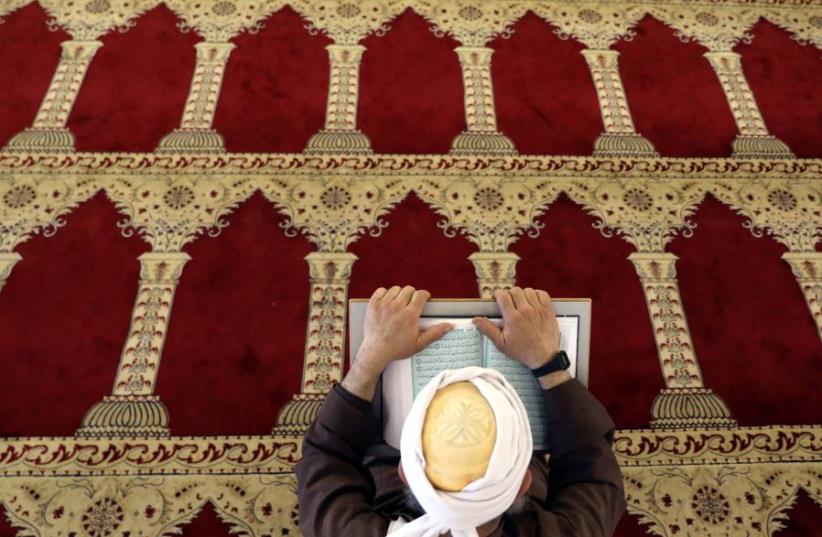 A Palestinian man reads the Koran in al-Aqsa Mosque in Jerusalem's Old City during the holy month of Ramadan (photo credit: REUTERS/AMMAR AWAD)