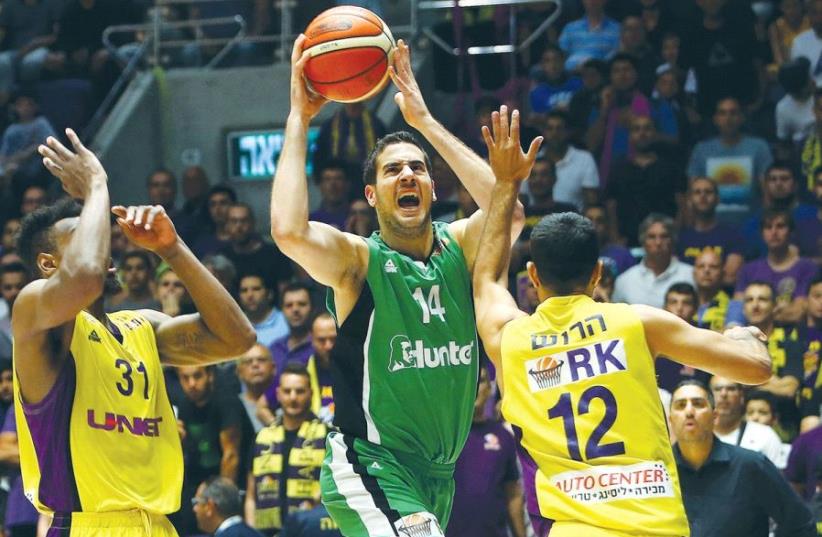 Maccabi Haifa forward Oz Blayzer (center) drives to the basket during last night’s 78-77 win over Hapoel Holon in Game 3 of their BSL quarterfinal series (photo credit: UDI ZITIAT)