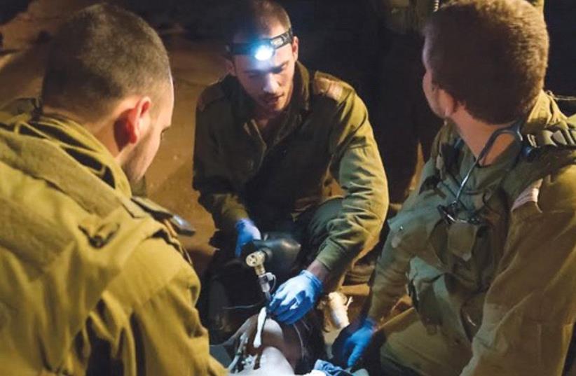 IDF SOLDIERS provide medical care to a wounded Syrian. (photo credit: IDF)