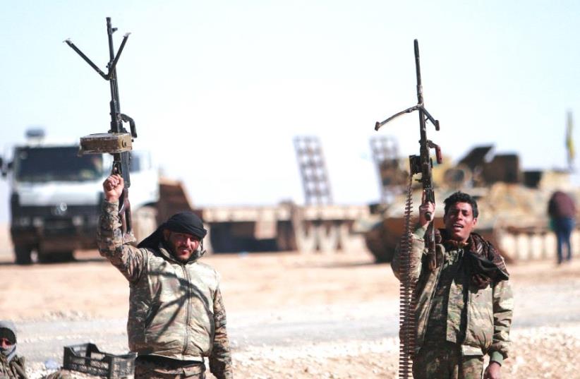 SYRIAN DEMOCRATIC Forces fighters hold up their weapons north of Raqqa city. (photo credit: REUTERS)
