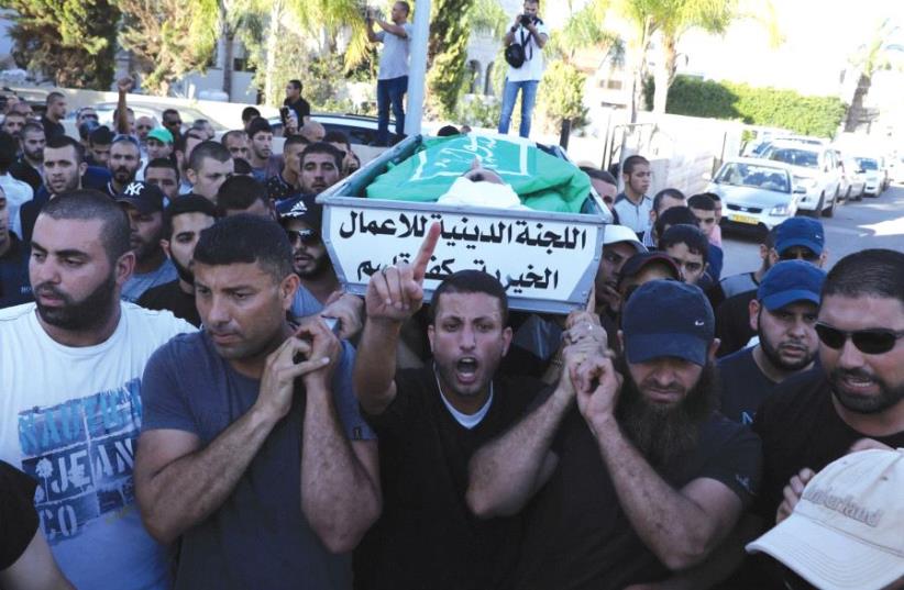 MOURNERS CARRY the body of Muhammad Taha at his funeral in Kafr Kasim, in the Triangle area east of Kfar Saba. Mayor Adel Badir accused police of routinely harassing people in the street. (photo credit: AMMAR AWAD / REUTERS)