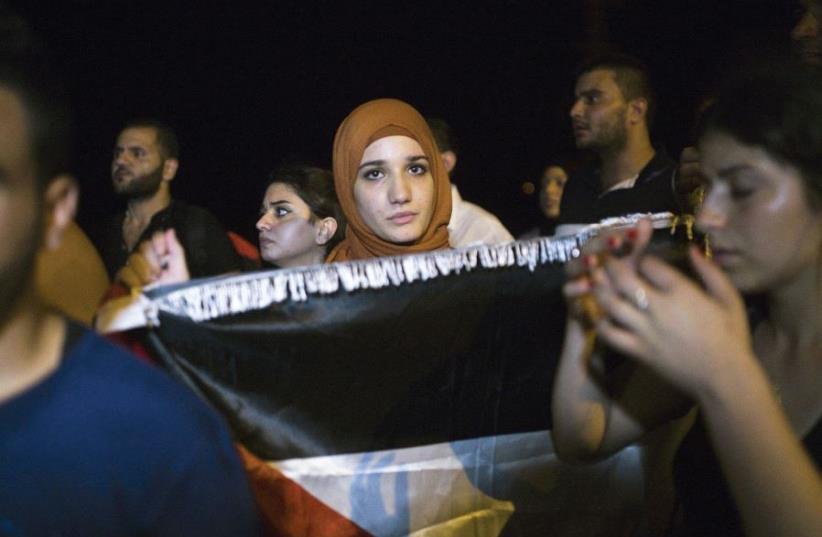 A woman holds a Palestinian flag as she attends a protest in support of a hunger-striking Palestinian prisoner in 2015 in Ashkelon (photo credit: AMIR COHEN - REUTERS)