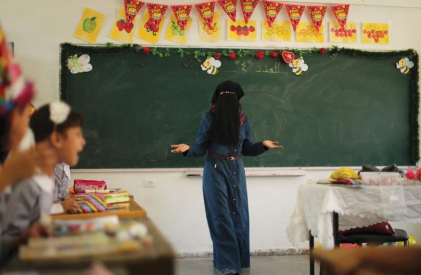 A PALESTINIAN TEACHER gestures as children attend a lesson at an UNRWA-run school in the Gaza Strip in 2015 (photo credit: REUTERS)