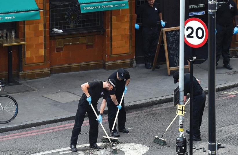 POLICE OFFICERS sweep the street outside a restaurant in Borough Market, near the scene of the recent attack in London (photo credit: REUTERS)