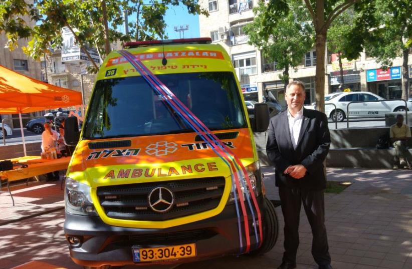  Dov Maisel poses Sunday next to the first mobile intensive care unit in Israel, dedicated in his uncle, Allen Beer’s, memory (photo credit: DANIEL K. EISENBUD)