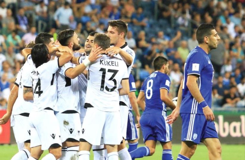 Albania pla yers celebrate their team’s opener in last night’s 3-0 victory over Israel in Haifa, with dejected blue-and-white defender Eitan Tibi (right) walking away in disgust. (photo credit: ERAN LUF)