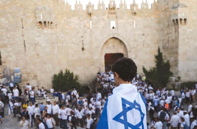A BOY wrapped with Israel’s national flag is seen during a parade marking Jerusalem Day last month outside the Old City Walls. Israel, the author argues, needs to assert more sovereignty (photo credit: REUTERS)