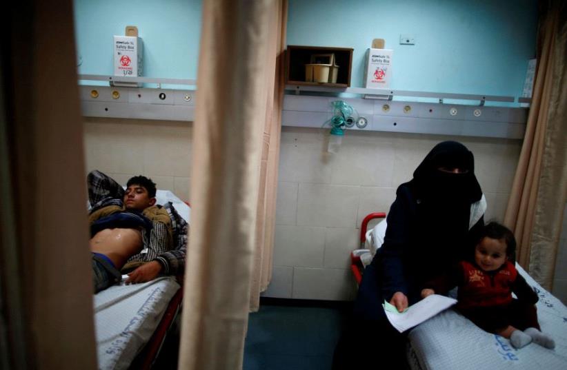 Palestinian boy Ahmed Abu Saman, 16, who was injured in a car accident, lies on a bed at the emergency department at Shifa hospital, Gaza's largest public medical facility, in Gaza City, March 29, 2017. (photo credit: MOHAMMED SALEM/REUTERS)