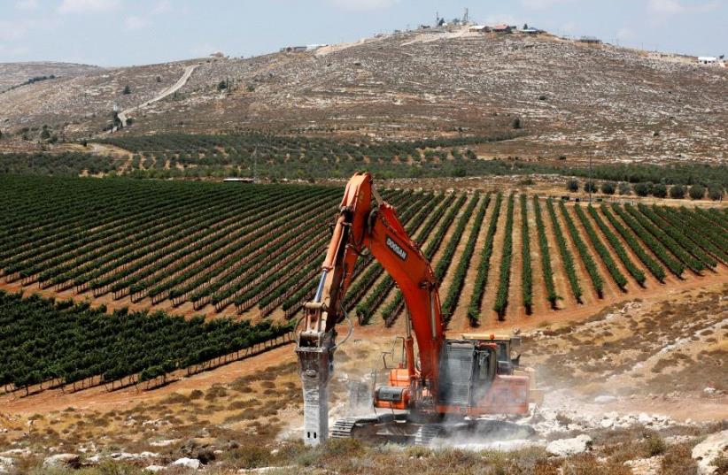 Heavy machinery work on a field as they begin construction work of Amichai, a new settlement which will house some 300 Jewish settlers evicted in February from the illegal West Bank settlement of Amona, in the West Bank June 20, 2017. (photo credit: REUTERS/Ronen Zvulun)