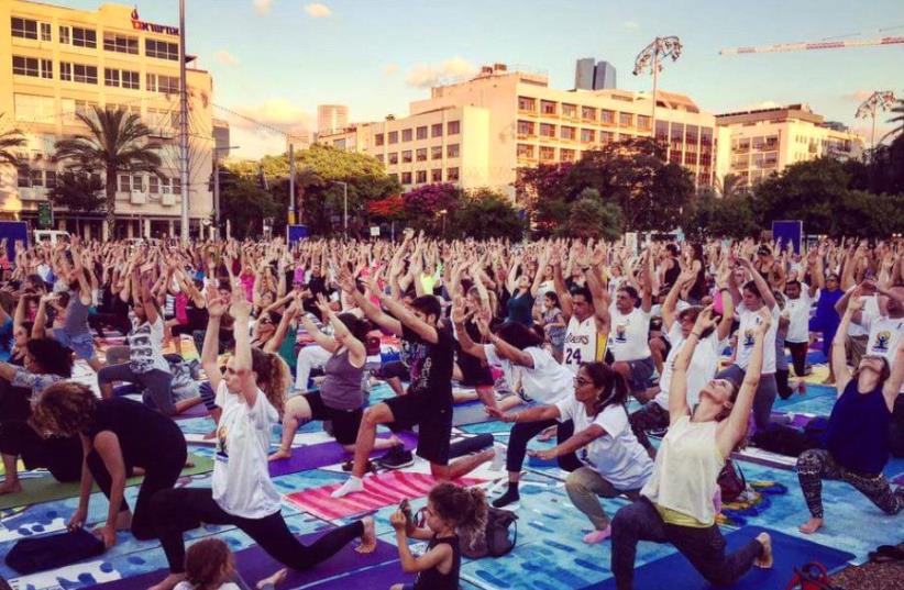 Participants take part in a communal yoga event in Tel Aviv to mark International Yoga Day, June 21 2017 (photo credit: ARSEN OSTROVSKY)