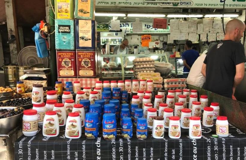  Karawan tahini (the blue jar) being sold alongside Al Arz tahini from Nazareth, and Yona tahini from Nablus at Tel Aviv's Carmel Market, May 19, 2017 (photo credit: ELIYAHU KAMISHER)