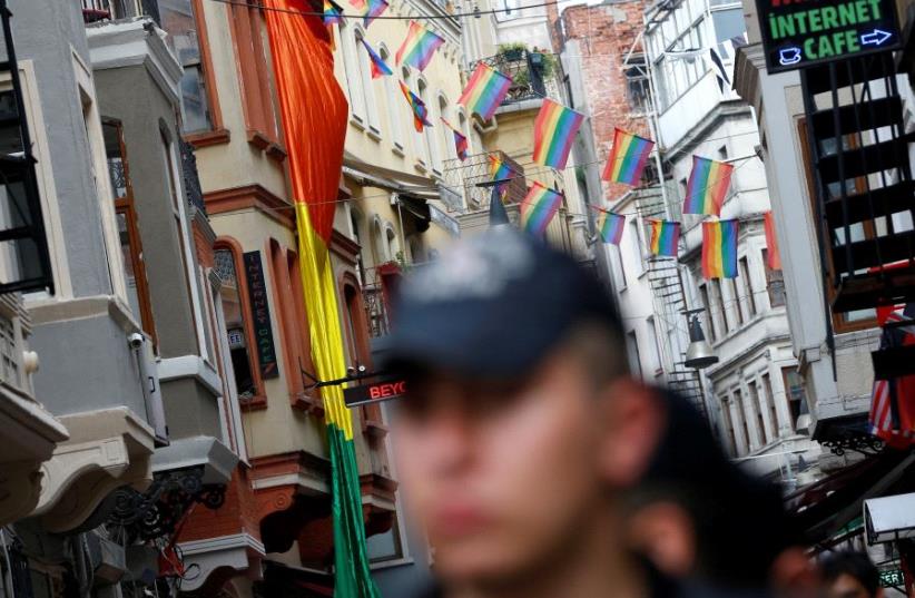 Riot police, with rainbow flags in the background, stands guard at the entrance of a street as LGBT rights activists try to gather for a pride parade, which was banned by the governorship, in Istanbul, Turkey, June 26, 2016 (photo credit: REUTERS/MURAD SEZER/FILE PHOTO)