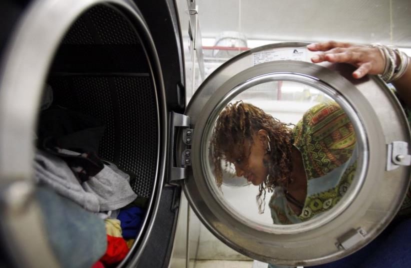 A woman loads laundry into the washing machine at a laundromat in Cambridge, Massachusetts July 8, 2009. (photo credit: REUTERS/BRIAN SNYDER)