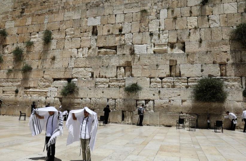 Youth hold their prayer shawls as they stand in front of the Western Wall, Judaism's holiest prayers site in Jerusalem's Old City May 17, 2017. (photo credit: REUTERS/Ronen Zvulun)