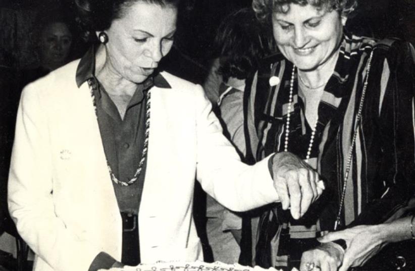 Raya Jaglom (left) helps Ziva Lahat, wife of then-Tel Aviv Mayor Shlomo Lahat, to cut the cake donated to WIZO Tel Aviv’s spring bazaar, in 1980 (photo credit: M. DEKEL)