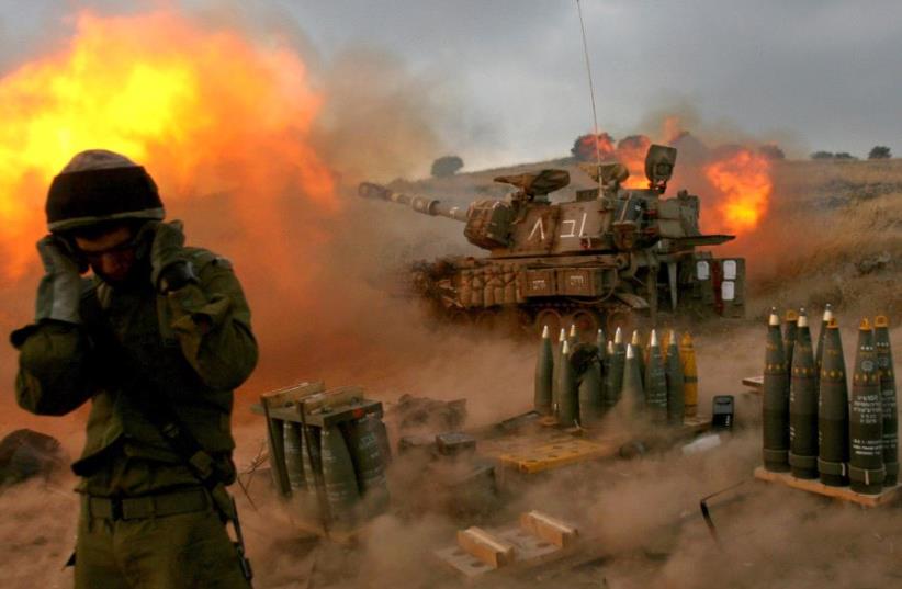 An Israeli soldier stands near a mobile artillery unit as it fires a shell into southern Lebanon from its position in Zaura, northern Israel, in this July 13, 2006 file picture.  (photo credit: REUTERS/GIL COHEN MAGEN)
