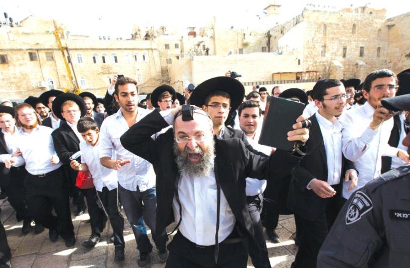 An ultra-Orthodox Jewish man holds a Bible as he protests against a monthly prayer session of the Women of the Wall group at the Western Wall, 2013 (photo credit: REUTERS)