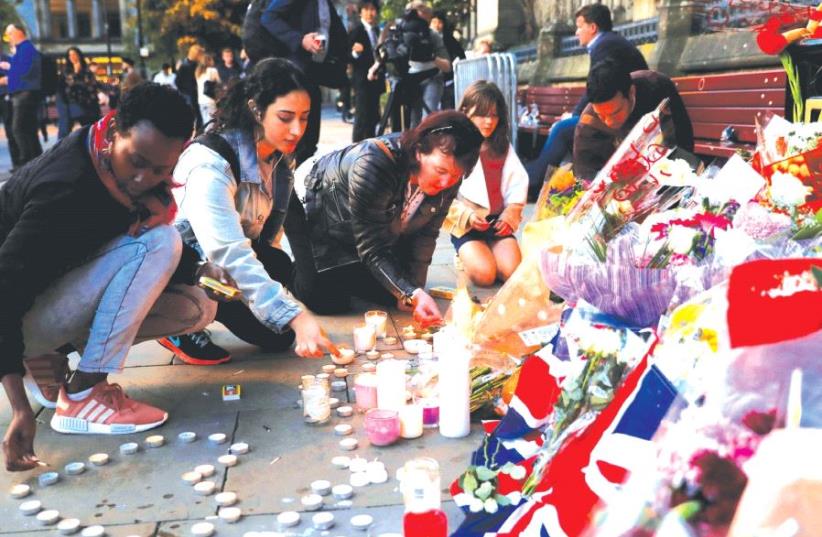 Women light candles for the victims of the Manchester Arena attack last month (photo credit: REUTERS)