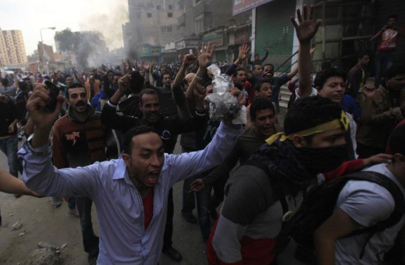 Supporters of the Muslim Brotherhood and ousted Egyptian President Mohamed Mursi shout slogans in front of riot police and army and their supporters, during clashes at El-Talbyia near Giza square, south of Cairo, November 29, 2013 (photo credit: REUTERS)