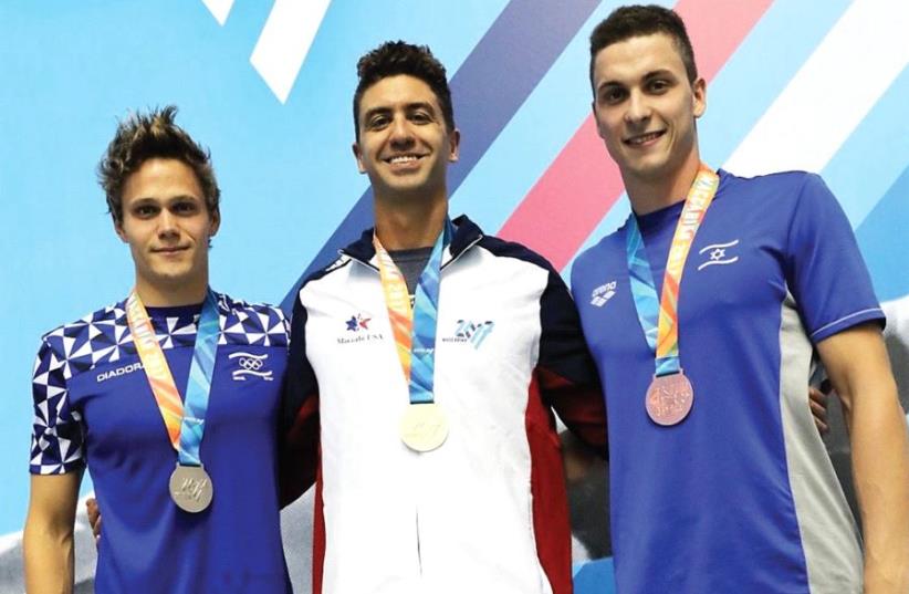 American swimmer Anthony Ervin (center) poses on the podium with fellow medalists, Israelis David Gamburg (left) and Alexi Konovalov, after winning his first gold medal of the 20th Maccabiah last night, finishing first in the 100-meter freestyle final at the Wingate Institute (photo credit: ITAMAR GREENBERG)