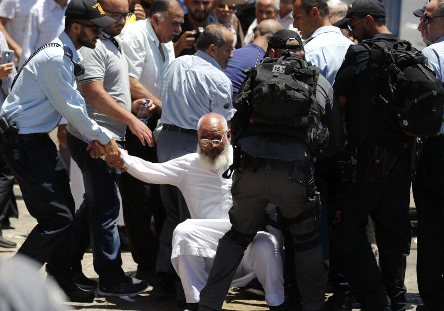Israeli security forces assist an older Muslim man in Jerusalem (credit: Thomas Coex/ Reuters)