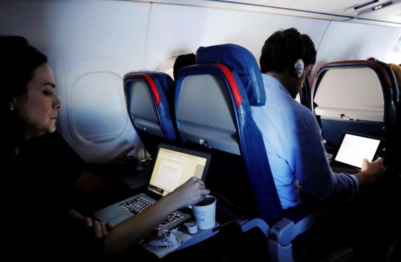 Passengers use their laptops on a flight out of John F. Kennedy (JFK) International Airport in New York, U.S., May 26, 2017. Picture taken May 26, 2017. (photo credit: REUTERS)