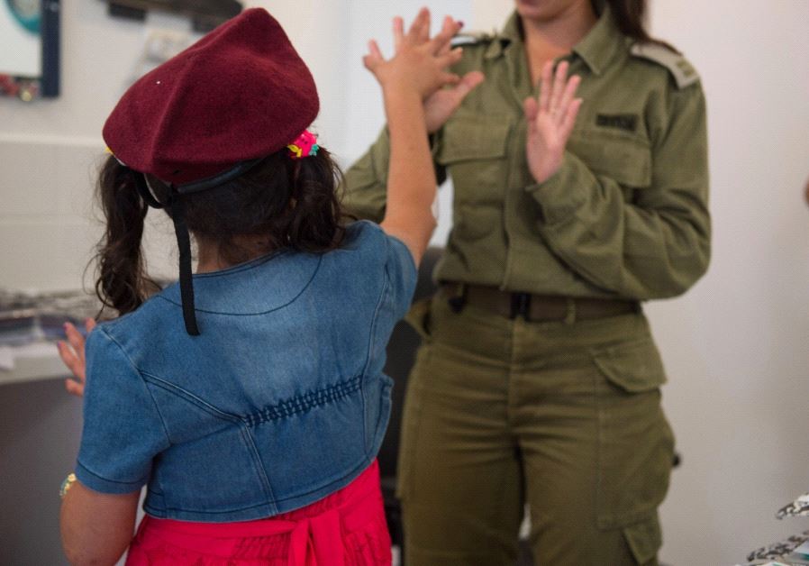 An IDF soldier plays with a Syrian child receiving humanitarian aid from Israel (Credit: IDF)