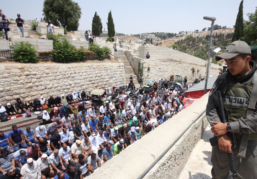 Israeli soldier looks on over mass prayer session (credit: Marc Sellem)