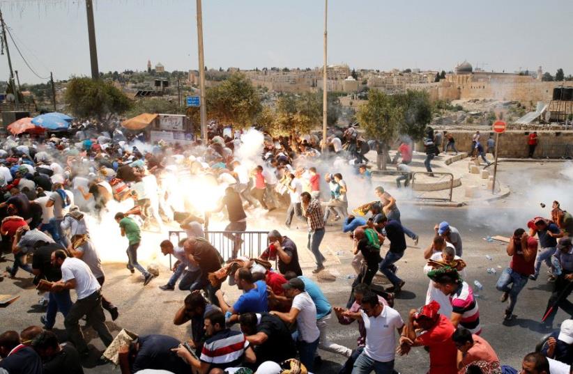 Palestinians react following tear gas that was shot by Israeli forces after Friday prayer on a street outside Jerusalem's Old city July 21, 2017. (photo credit: REUTERS/AMMAR AWAD)