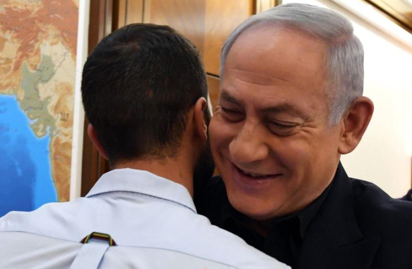 Israeli Prime Minister Benjamin Netanyahu hugs the security guard from the Israeli embassy in Amman Jordan who was stabbed by a terrorist (photo credit: CHAIM TZACH/GPO)