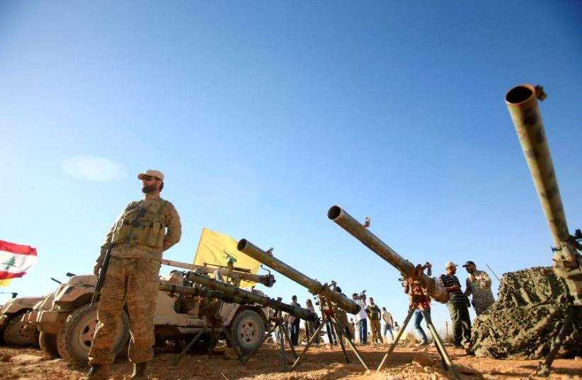 A Hezbollah fighter stands in front of anti-tank artillery at Juroud Arsal (photo credit: ALI HASHISHO/REUTERS)