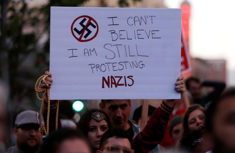 A demonstrator holds signs during a rally in response to the Charlottesville, Virginia (photo credit: REUTERS/STEPHEN LAM)