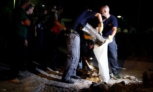 Police officiers remove the remains of Grad rocket - Photo: REUTERS/Amir Cohen