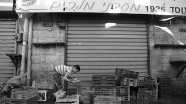 A BOY moves vegetables from a crate to a nearby store.