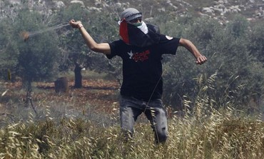 Palestinian uses sling to throw rocks at IDF near Deir Jarir in the West Bank, May 17, 2013.