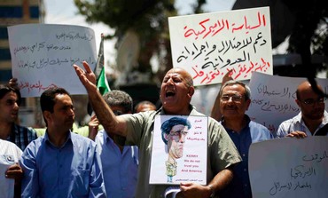 Palestinian protester holds a poster with a caricature of John Kerry in Ramallah May 23, 2013.