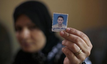 Wife of Palestinian Wael Abu Rida holding his picture.
