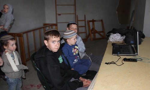 Children playing with a computer in the Levinger's apartment in Beit HaShalom.