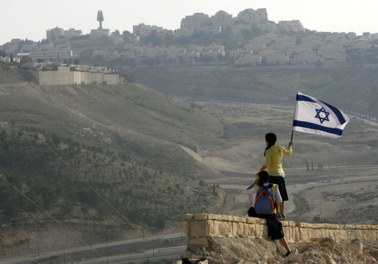 A girl holds an Israeli flag on a hilltop near the Maaleh Adumim settlement