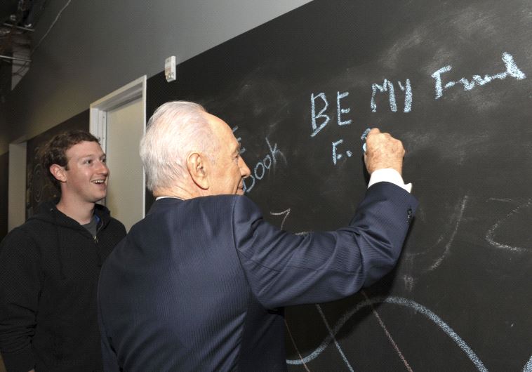  Shimon Peres writes on a blackboard with Facebook's CEO Mark Zuckerberg at the company's headquarters in Menlo Park, California, March 2012 (photo credit: REUTERS)