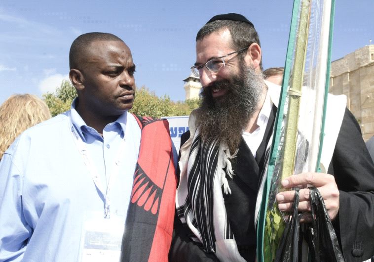 MP Rev. Malani Mtonga of Malawi (left) speaks with a Succot celebrant in Hebron (photo credit: AVI HAYUN)