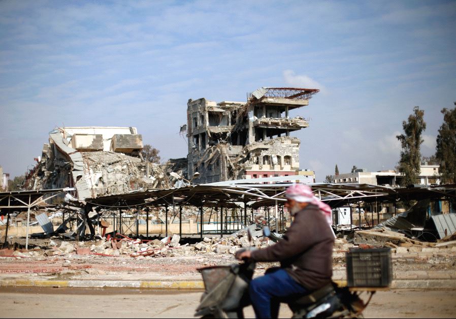 A man rides by the ruins of the University of Mosul, January 30. The university was destroyed in fighting between the Iraqi army and Islamic State. Much of the city has suffered massive damage during the fighting (photo credit: REUTERS)