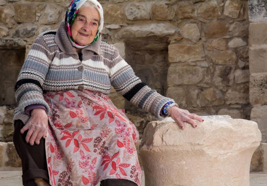 Margalit Zinati, of the Peqi’in village, poses with the ancient stone. (Courtesy of Beit Zinati)