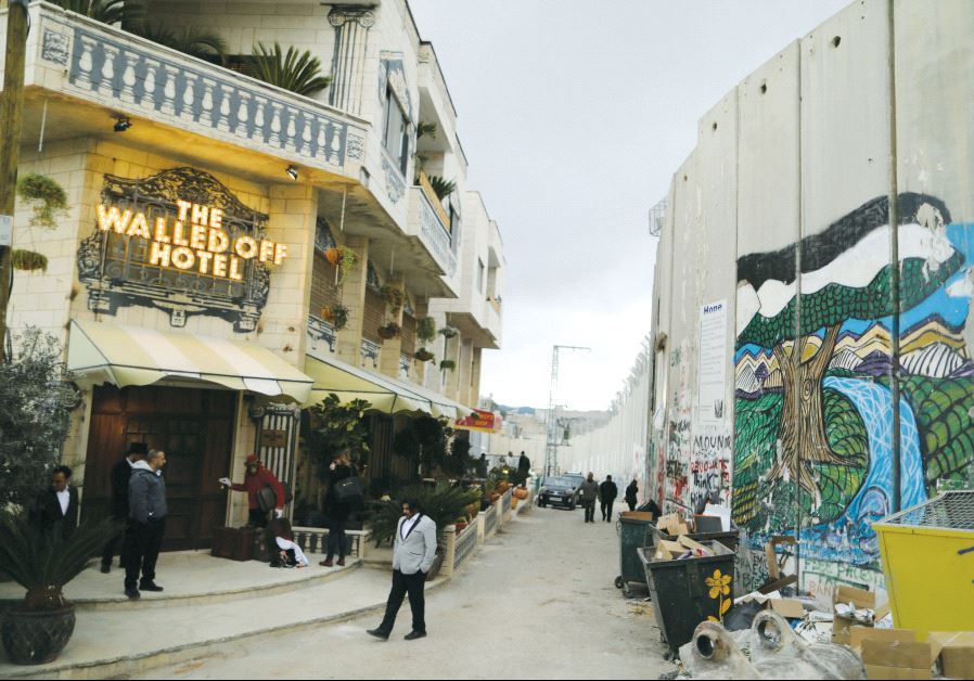 People stand outside the Walled Off Hotel, which was opened by street artist Banksy, in Bethlehem (photo credit: REUTERS) 