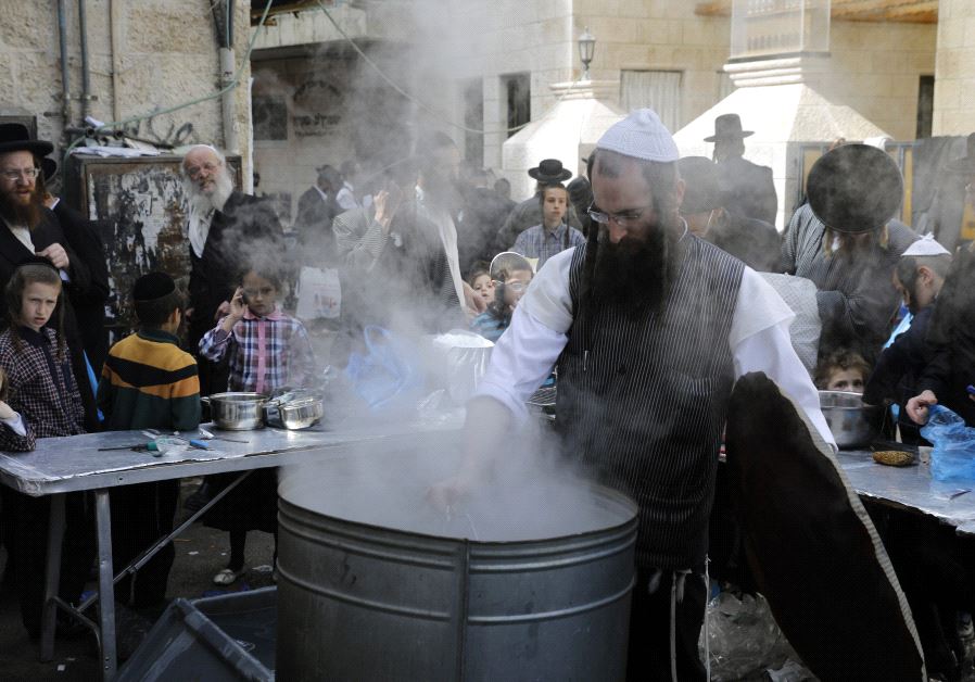 Ultra-Orthodox Jewish men dip in boiling water their cooking utensils to remove remains of leaven in preparation for Passover in Jerusalem's Mea Shearim neighbourhood on April 9, 2017 (MENAHEM KAHANA/AFP) 