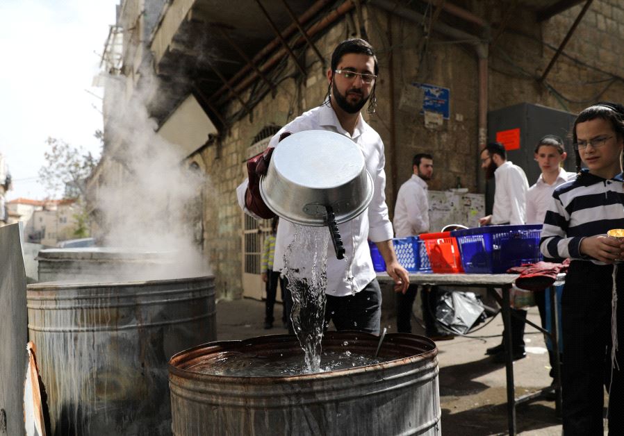 Ultra-Orthodox Jewish men dip in boiling water their cooking utensils to remove remains of leaven in preparation for Passover in Jerusalem's Mea Shearim neighbourhood on April 9, 2017 (MENAHEM KAHANA/AFP)